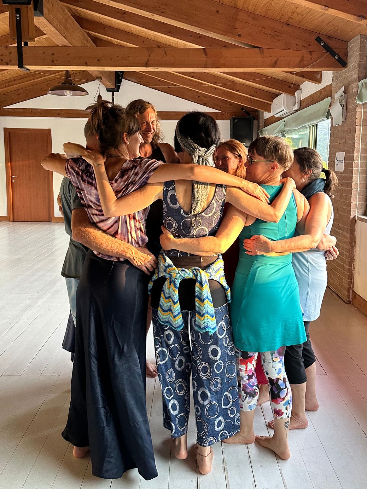 A circle of people embracing in a wooden studio
