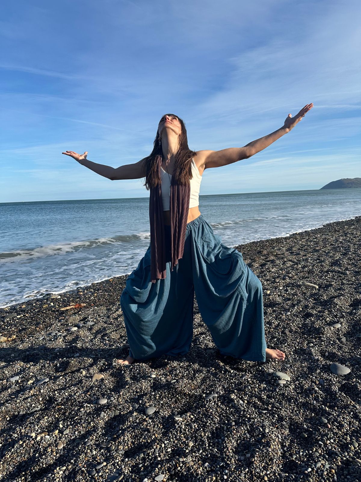 Gita dancing on a pebble beach with arms outstretched